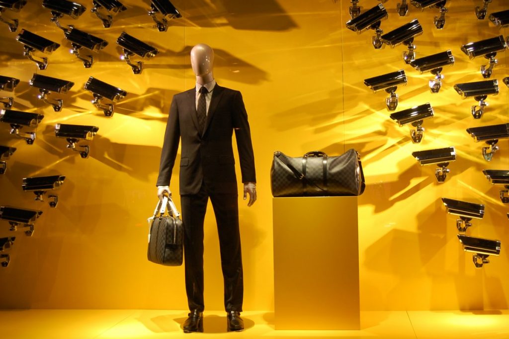 Eine Schaufensterpuppe mit zwei Taschen auf die unzählige Kameras gerichtet sind